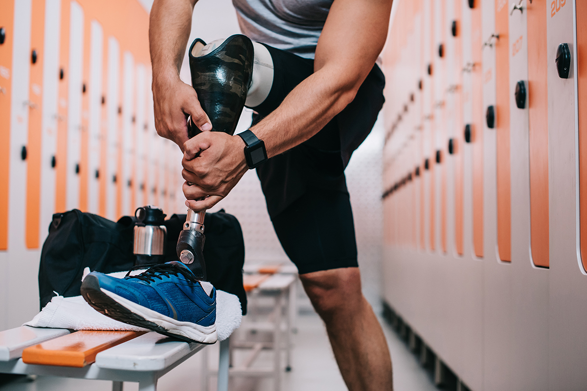 A man putting on a prosthetic leg in a locker room.