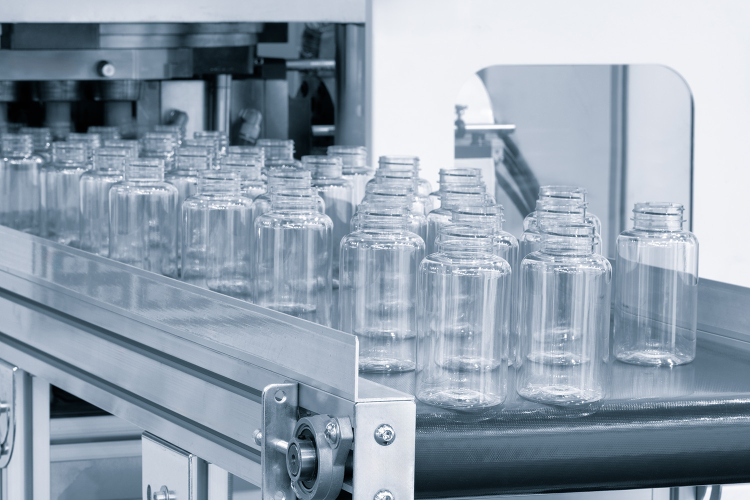 Thermoplastic molding showcased with clear bottles on a conveyor belt.