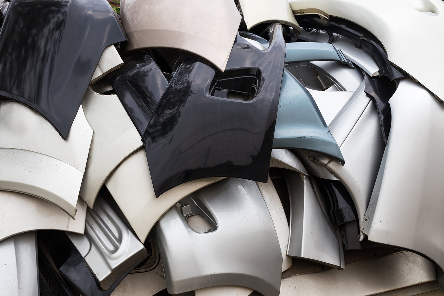 A pile of plastic car bumper parts in different colors.
