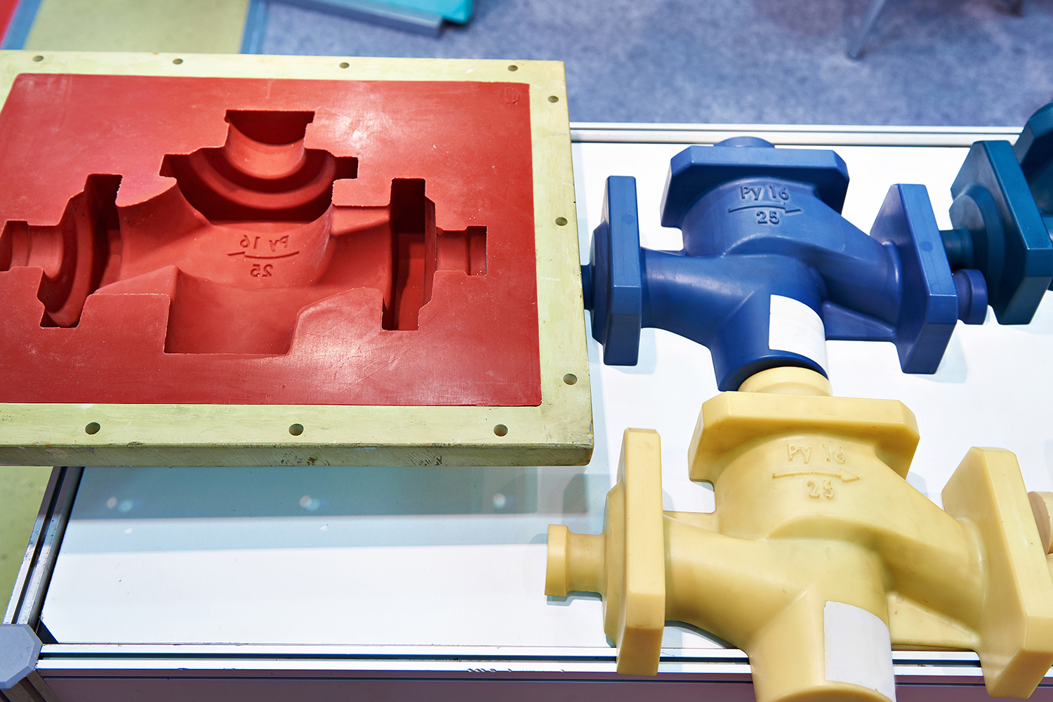 a red rubber mold and a blue and yellow product produced off that mold