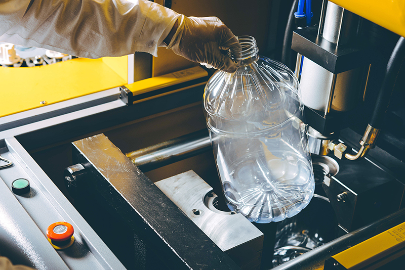 A metal mold for plastic products, with a clear plastic bottle coming off the mold.