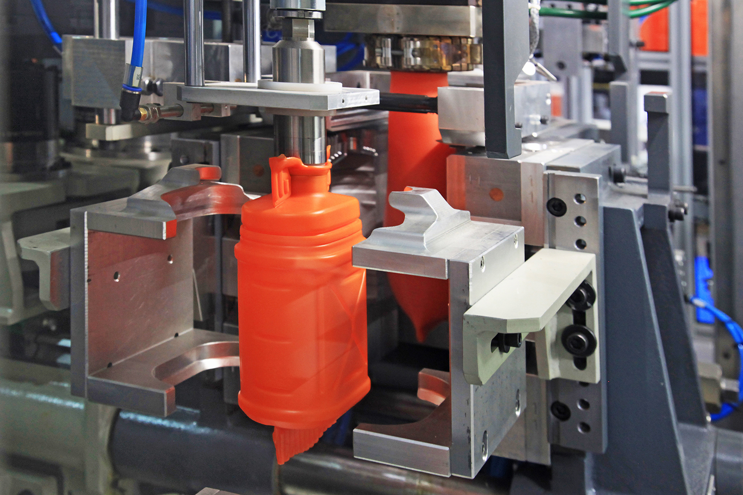 Industrial plastic cans in production on a manufacturing line.