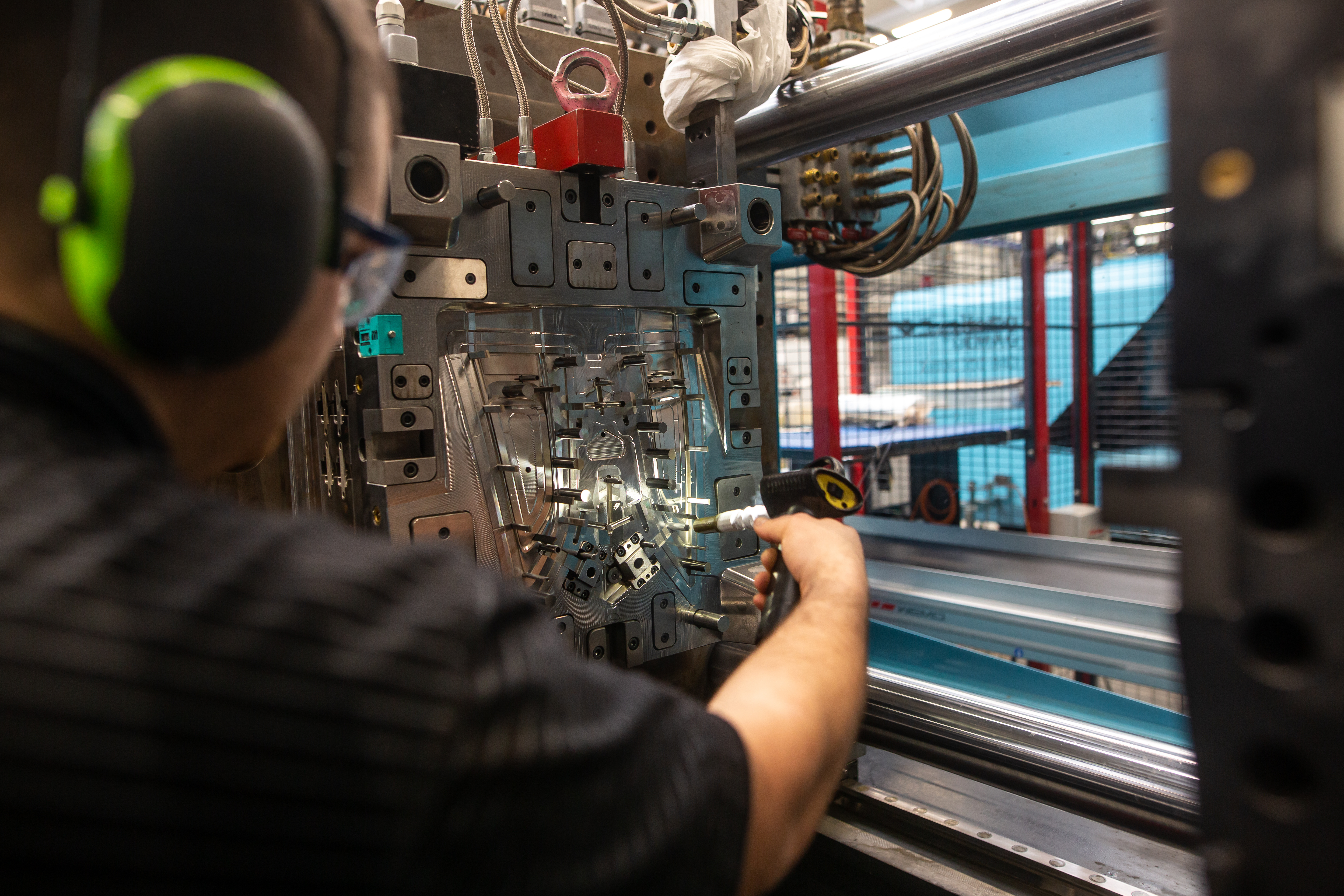 A molding industry professional conducting maintenance on an injection molding device