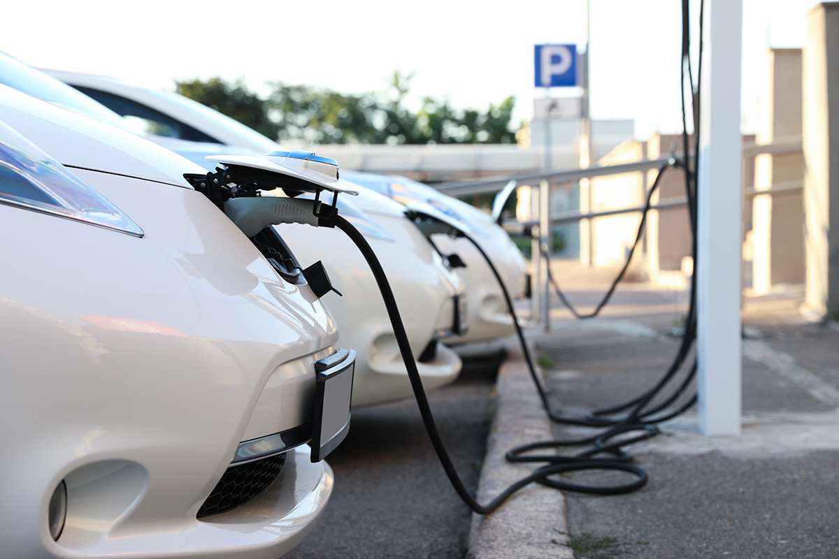 White electric vehicles lined up and charging at an EV charging station.