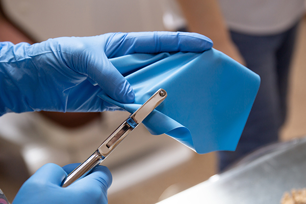 A medical professional’s hands in rubber gloves, manipulating a rubber medical sheet