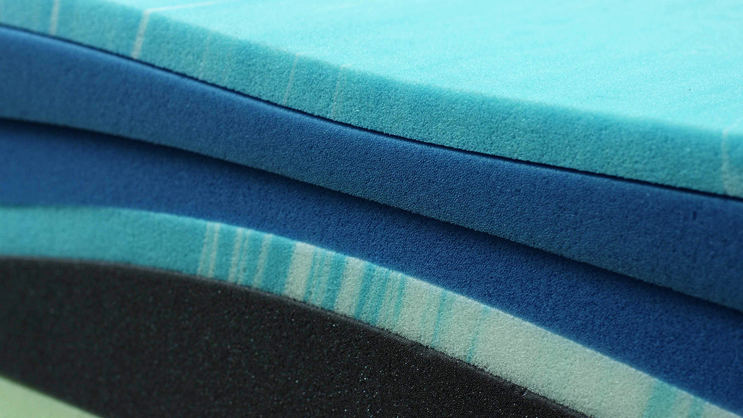 A stack of blue, light blue, and black polyurethane foam for a mattress.