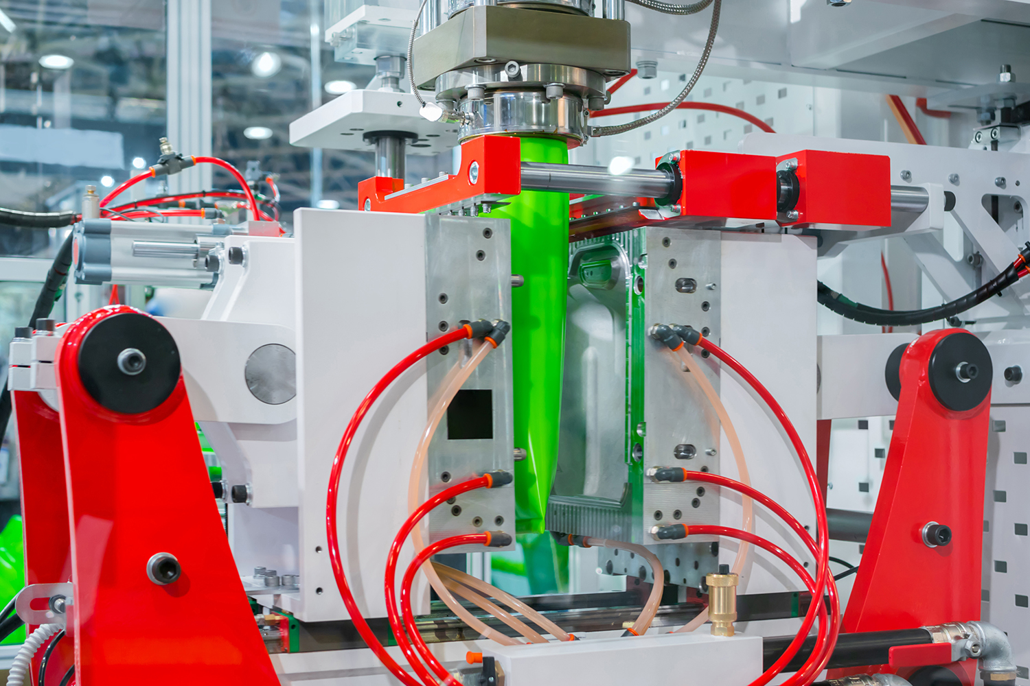A blow molding machine making large green bottles.