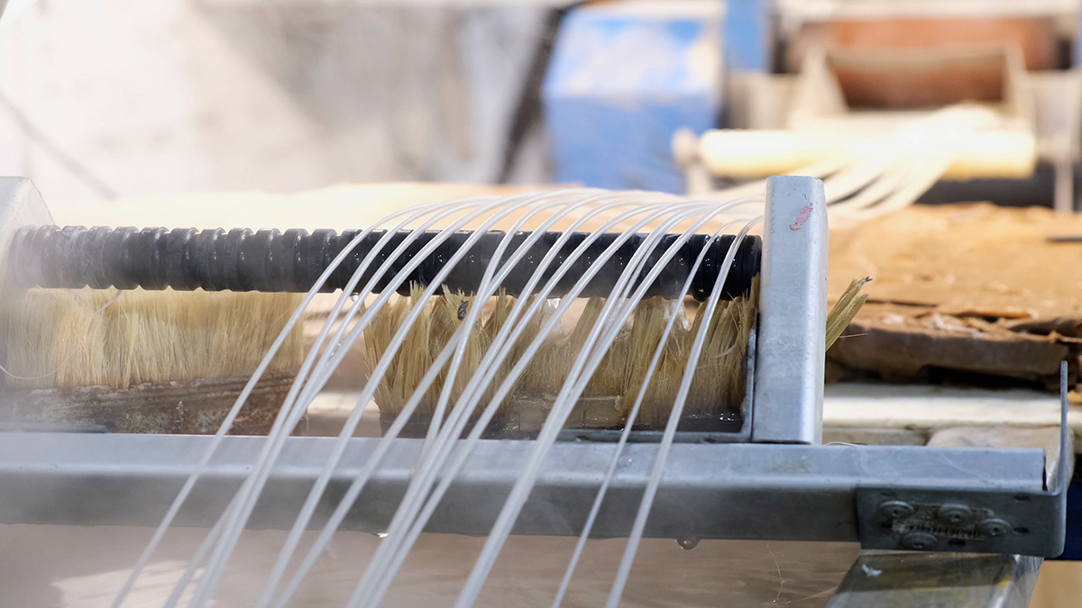 A view of several plastic ropes as they are drawn across a cooling roller.