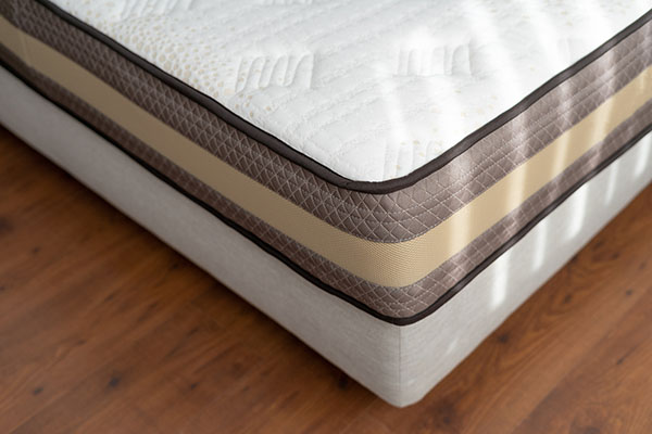 A corner of a memory foam mattress on top of a wooden floor