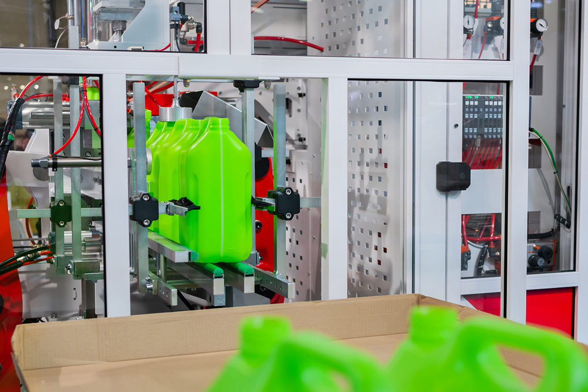 Bright green plastic bottles on conveyor belt after being molded.