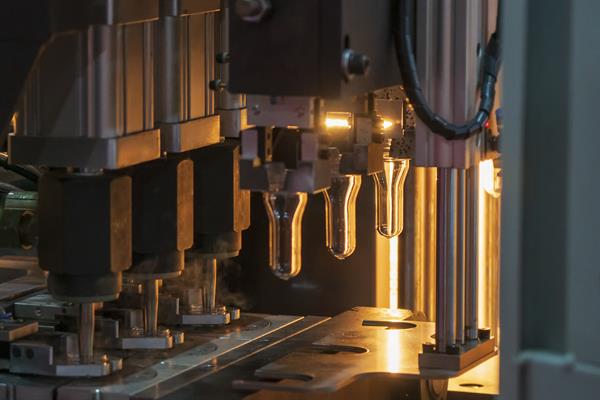 A plastic blow-molding machine extrudes a water drinking bottle.