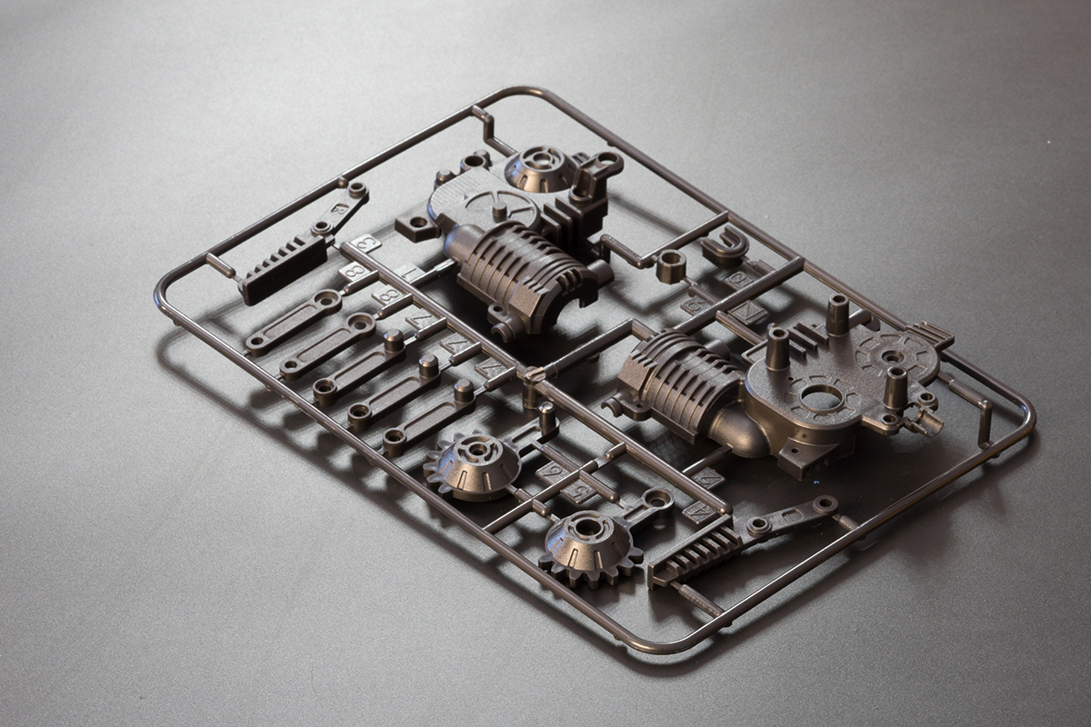 Black plastic parts still attached to runners and sprues from injection molding.
